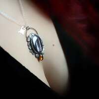 Un bijou de Magie Partagée 🖤
Notre Route des Sorcières poursuit son chemin en terres celtes 🧡
Le conte de Jack nous guide jusqu’en Irlande, là où les landes s’étendent à perte de vue, baignées de brumes mystérieuses ☁️
Ici, chaque pierre, chaque arbre, chaque souffle de vent murmure encore l’écho de récits anciens ✨
Car si Halloween règne aujourd’hui, c’est en vérité Samhain qui demeure, plus ancien, plus profond 🧙🏻♀️
C'est ici que notre nouveau " Bijou de Magie Partagée " est né, tissé de vos choix et de vos inspirations, guidé par mes mains et un peu de magie ✨️
Un concept unique, signature et protégé, de l'atelier depuis 2022. Comme pour chaque collection depuis, c'est vous qui choisissez ( votes en story ) le chemin que nous prendrons, pour créer un bijou unique, ensemble 🤝
Vous choisissez la pierre, la forme qu'elle prendra, le thème que l'on travaille, et moi je mets mes mains à votre service pour lui donner vie à l'atelier 🤲✨️
Une jolie façon de vous lier encore plus à votre bijou 🖤
Cette fois, vous avez élu une mystérieuse pierre d'hypersthène au noir profond ✨ Vous m'avez demandé d'en faire un collier sur le thème du voile entre les mondes 🕯️
Voici ce que j'ai imaginé pour vous.
Un médaillon unique, en argent massif 925, entièrement réalisé à l'atelier.
J'ai voulu représenter le voile entre les mondes au moment de l'année où il est le plus fin, à Samhain 🧙🏻♀️
Je l'ai accompagné d'une merveilleuse ambre au feu puissant pour éclairé la saison sombre, et entouré d'une ronde de feuilles d'automne pour former le passage ✨
En superposition un petit médaillon fantôme viendra vous accompagner au gré de vos envies, suivant de quel côté du voile vous souhaitez être.. 👻
J'espère qu'il vous plaira autant qu'à moi 🙏
Maintenant, il ne manque qu’une chose, lui choisir son nom.
Un nom qui capturera la magie de ce bijou que nous avons tissée ensemble 🕯️🧙🏻♀️🖤
Laissez-moi vos idées en commentaire, j’en choisirai trois, et nous voterons en story pour élire le nom de ce nouveau " Bijou de Magie partagée ".
Laissez parler votre cœur, votre imaginaire 🖤
Merci pour cette nouvelle aventure à vos côtés ✨