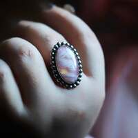 Le refuge des rêves ☁️🩷 

C'est ici que notre voyage commence, au creux d'un ciel rose, doux comme une caresse 🩷 

On dit qu’il apparaît quand nos rêves cherchent un refuge. 
Un ciel qui ne tombe jamais dans la nuit, un ciel de rose suspendu, gardé par les nuages et le silence ☁️ 

Ceux qui lèvent les yeux au bon moment, y déposent leurs rêves les plus fragiles, et en retour, le ciel leur offre un peu de tendresse 🩷 

Peut-être que regarder le ciel,
c’est déjà commencer à rêver autrement ? 

Ce soir c'est une bague unique que je vous présente ✨ En argent massif 925, taille ajustable, et entièrement réalisée main par mes soins à l'atelier 🤲🏻 

Elle protège en son cœur une incroyable pierre d'Agate plume doublet dans laquelle se dessine un merveilleux ciel rose aux reflets holographiques de magie 🩷☁️ 

Pour toujours garder le refuge de vos rêves à portée des doigts ✨ 

C'est l'une des rares fois où j'utilise une pierre transformée par l'homme. Mais je suis tout de suite tombée amoureuse de ces agates ciels. 

L'agate plume doublet est une pierre d'agate plume naturelle qui a été doublée par un fond de couleur. Comme ici avec un fond rose à reflets holographiques. Pour faire ressortir son côté nuageux merveilleux 🥹☁️ 

Pièce unique, disponible lundi 23 mars à 20h pour la sortie de la nouvelle collection Les Couleurs du Ciel ~  🌅☁️✨ 

#cybijoux #jewelry #skylover #sky #celestialjewelry