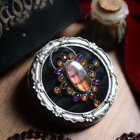 Les voix de Salem 🧙🏻♀️ 
Sous la cendre du temps, vingt flammes demeurent. Vingt noms murmurés dans l’ombre des bois, vingt visages effacés par la peur mais gravés dans la mémoire des pierres de Salem 🕯️ 
Les accusés des procès de Salem. Offerts au silence d’une justice dévoyée, condamnés pour leur liberté. Reflets d’une société en proie à ses démons, d’un pouvoir nourri de peur et de fanatisme. 
Elles furent sorcières, ils furent sorciers. Leurs voix étouffées qui résonnent maintenant comme un chant de liberté. Leur héritage n’est pas celui de la peur, mais celui du courage. 
Dans la magie des pierres, dans chaque geste qui honore l’invisible, on entend encore leur souffle qui défie l’oppression et s’élève au-dessus des flammes et des cordes 🔥 
Vingt pierres pour vingt éclats de mémoire. Une pierre pour chaque âme.
Une étincelle pour chaque destin brisé. 
Chacune porte l’ombre d’un nom, la magie d'une mémoire. Ensemble, elles forment un talisman sacré contre l’injustice et la peur. 
Ce bijou est une offrande pour les âmes libres. Une incantation de mémoire et de puissance. Porter ces pierres, c’est porter leurs voix 🧡 
Bridget Bishop, Sarah Good, Elizabeth Howe, Susannah Martin, Rebecca Nurse, Sarah Wildes, George Burroughs, George Jacobs Sr., John Proctor, Martha Carrier, John Willard, Martha Corey, Mary Eastey, Mary Parker, Alice Parker, Ann Pudeator, Wilmot Redd, Margaret Scott, Samuel Wardwell, Giles Corey 🕯️ 
Pour rendre hommage aux 20 condamnés lors des procés de sorcellerie de 1692, j'ai créé un médaillon unique, une master pièce de cette collection, entièrement faite main en argent massif 925. 
20 pierres pour 20 âmes ✨
Une synergie puissante et profonde, d'une labradorite violette et feu, de pierre de grenat au rouge intense, d'améthyste au violet mystique, de grenat hessonite et d'ambre baltique a l'orange lumineux 🔥 
Un magie puissante réunie en un seul et même médaillon talisman 🧙🏻♀️ 
Au dos, comme un secret rien qu'à nous, j'y ai gravé un à un ces mots " Notre magie ne s'éteindra jamais " pour ne jamais oublier que nous sommes l'héritage des voix de Salem 🧙🏻♀️✨ 
Pièce unique, disponible le lundi 13 octobre à 20h 🧡