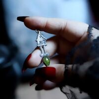 Baba Yaga - L'épreuve 🌲 
Notre route des sorcières se poursuit, et ce soir elle serpente entre brumes et racines ☁️ 
Nous voici arrivés au cœur des vastes forêts Slave. Là où les ombres se perdent dans les sapins. L’air a changé, plus lourd, plus sauvage, traversé d’une odeur de terre humide et de feu ancien. C'est ici que les contes prennent vie.. 🔥 
Nous sommes arrivés, voyageurs de l’ombre, devant le seuil où se décide le destin ✨ 
Une nouvelle sorcière se présente à nous, la Baba Yaga, la vieille aux os de fer et aux yeux de braise 🌲 
Sa maison, montée sur des pattes de poule, veille dans les profondeurs des bois, tournant sur elle-même puis vers ceux qui osent s’approcher. Ce lieu n’appartient à nul autre qu’à elle, gardienne des passages, dispensatrice d’épreuves, maîtresse des secrets qu’on n’arrache qu’au prix de sa peur 🧙🏻♀️ 
Si la Baba Yaga effraie, elle n’est pas que peur, elle est aussi l’épreuve nécessaire. À ceux qui osent franchir sa porte avec courage et respect, passer ses épreuves avec brio, elle offre bien plus que la peur. Un savoir qui éclaire la route, un feu précieux pour accomplir votre mission, l'étincelle de vie qu'il vous manque.. 🔥 
Ainsi, dans son ombre se cache aussi une force bienveillante, celle d’une mère sauvage qui enseigne la transformation. Elle peut donner ou détruire, nourrir ou dévorer. Elle est une force archaïque qui teste la valeur de l'héroïne ou du héro qui sommeille en vous 🖤 
Car rencontrer Baba Yaga, c’est affronter l’inconnu pour renaître plus fort, grandi, porteur d’un feu nouveau 🔥
Alors, accepterez-vous ses épreuves ? 
Ce soir c'est un collier unique que je vous présente, en argent massif 925, toujours entièrement fait main à l'atelier ✨ 
Un médaillon talisman à l'honneur de Baba Yaga 🧙🏻♀️ Sa cabane si singulière ornée d'une merveilleuse pierre de vésuvianite au vert mousse mystique 🌲 
Pour toujours garder son pouvoir de transformation près de vous 💚 
Pièce unique, disponible lundi prochain, le 13 octobre à 20h pour la nouvelle collection ~ La route des Sorcières ~ 🧙♀️🐈⬛✨