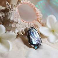 Pāua - L'éclat du Mana 🌀 

Un éclat de Mana figé dans la lumière ✨️ 

Pour le peuple Maori, l'abalone appelée Pāua n’est pas un simple coquillage, c'est une nacre sacrée, un trésor né des abysses, façonné par la magie du dieu Tangaroa aux couleurs du monde, vibrant d’énergie et porteur d’histoire 🐚 

Un éclat de Mana, cette force invisible qui anime toute chose et qui tisse l’univers. Le Mana, c’est la puissance des dieux, le souffle vital des ancêtres, le lien entre le tangible et l’invisible. Et dans la coquille du Pāua, le Mana trouve un écrin, un reflet précieux ✨️ 

Dans les traditions maories, on incrustait la nacre dans les yeux des sculptures sacrées, pour y déposer la puissance, l’âme et la vigilance des ancêtres. Car le Pāua est un regard éternel, il voit au-delà des voiles, il garde et protège. 
Il ouvre les portes d’un autre monde 🩵 

L’union du Pāua et du Mana forme ensemble une protection puissante. Leurs magies portent en elles la force des ancêtres, l'ouverture entre les mondes et la protection des océans ✨️ 

Ce soir c'est un médaillon unique que je vous présente en argent massif 925 et toujours entièrement fait main par mes soins à l'atelier  🙌 

Une abalone d'une qualité incroyable, aux reflets irisés merveilleux dans laquelle j'ai tout de suite vu couler la magie du Mana 🙏✨️ 

Je l'ai habillé d'argent et accompagné d'une pierre délicate de cyanite au bleu profond 🩵 

Au dos, pour renforcer sa puissance j'y ai gravé le mot " Mana " pour toujours garder cette force près du coeur 🙏 

Pièce unique, disponible lundi prochain, le 28 juillet à 20h pour la nouvelle collection ~ Les Chants Du Pacifique ~ 🏝🌺🐚 

#cybijoux #metalsmith #silverjewelry #jewelry #jewellerydesign #summer #silver #handmadejewelry #polynesian #tahiti #maori #hawaii #polynesia #newzealand #aotearoa #handmadejewelry #tahitianpearljewelry #tahitianpearls #tiki #mana #koru #tribal #tatau #sea #polynesianjewelry #tahitianjewelry #maorijewelry #moana #wales #mana