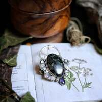 Belladone - La belle dame 💜 

Elle pousse là où la lumière s’efface.
Aux creux de clairières oubliées, à la lisière de mondes anciens. 

La Belle Dame 🧙‍♀️
Ses baies noires, luisantes comme des perles d'encre précieuses et ses fleurs au violet intense ont le pouvoir de charmer ou d’ensorceler.
Puissante, toxique et divine 💜 

Plante des sorcières par excellence et des visions, elle ouvre les portes du rêve et du vertige, elle protège ou égare, selon les mains qui la cueille 🍃 

En magie elle est utilisée dans des rituels de divination, pour voir au delà du voile. Elle ouvre des portes secrètes, offre rêves et visions où les esprits parlent à voix basses. Mais gare à vous, à juste dose, le rêve peut vite se transformer en cauchemar si une sorcière l'a décidé.. 🧙‍♀️ 

Voici ce soir la toute dernière master pièce de cette collection 🍃 Un collier talisman en argent massif 925 entièrement fait main à l'atelier ✨️ 

La belle belladone 🥀 

Elle portège une merveilleuse pierre de jaspe kambaba au vert et au noir intense comme notre plante, puis une incroyable pierre de iolite au violet sombre et profond comme ses fleurs délicates 💜 

J'espère qu'elle vous plaira autant qu'à moi 🧙‍♀️ 

Pièce unique, disponible demain, lundi prochain le 19 mai à 20h pour la nouvelle collection ~ Sorcières Vertes ~ 🌿🧙‍♀️🍵 

#cybijoux #metalsmith #bijouterie #magic #witch #witchlife #jewelry #jewellerydesign #ladysmith  #faitmain #handemade #greenwitch #green #mysticjewelry #slowcraft  #witchvibes #naturalwitch #plants #silverjewelry #botanical #forest #witchjewelry #naturemagic #forestwitch #magicaljewelry #herbalwitch #esoteric #artisanbijoutier #flower #garden