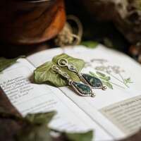 Terre Mère - Les murmures du Monde 🌍 

Elle parle. Elle ne crie pas, elle vous murmure.. À qui tend l’oreille, la Terre Mère confiera ses secrets 🌍 

De celle qui enfante le monde et recueille nos silences 🌱 

Les anciens disaient que tout a une voix. La pierre qui attend, l’arbre qui veille, les racines qui puisent, l’eau qui danse.. 🌊 

Écoutez. 
Elle est là. 
Sous vos pieds, dans vos souffles. Vous n'êtes jamais seuls, partout elle veille sur vous 🙏 

Dans mes mains, ses murmures prennent forme 🍃
Vous entendez ? 

" Respirez.. le monde n'a pas besoin de vitesse, il a besoin de présence. Vous êtes exactement là où vous devez être 🌱🙏🌍 "

Assorties à notre médaillon, ce soir c'est une délicate paire de boucles d'oreilles que je vous présente ✨️ Douces et légères à porter, en argent massif 925 et toujours entièrement réalisées main à l'atelier 🔥 

Le symbole de la Terre Mère qui protége d'incroyables pierres d'agate mousse dans lesquelles vous pouvez voir s'y dessiner tout un monde 🌍 

Pour murmurer à vos oreilles la sagesse ancestrale de la déesse primordiale 🙏✨️ 

Pièce unique, disponible le lundi 19 mai à 20h pour la nouvelle collection ~ Sorcières Vertes ~ 🌿🧙‍♀️🍵 

#cybijoux #metalsmith #bijouterie #magic #witch #witchlife #jewelry #jewellerydesign #ladysmith  #faitmain #handemade #greenwitch #green #mysticjewelry #slowcraft  #witchvibes #naturalwitch #plants #silverjewelry #botanical #forest #witchjewelry #naturemagic #forestwitch #magicaljewelry #herbalwitch #gaia #artisanbijoutier #flower #Instawitch